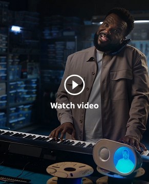 Craig standing in a workshop, jamming out on an electric keyboard with the Wake Up with Craig clock in front of it. He's on the phone, nestled between his ear and shoulder.