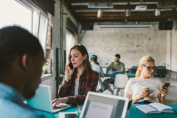 Coworkers working in an open space office. Sitting by the desk and using their smart phones,Coworkers working in an open space office. Sitting by the desk and using their smart phones