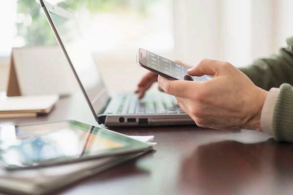 Close up of mans hands working at desk with computer, phone and tablet,Close up of mans hands working at desk with electronic devices